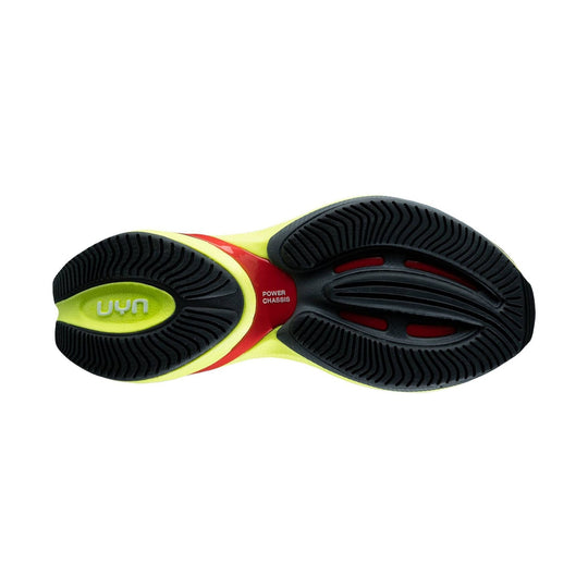 Running shoe outsole with black tread, neon yellow accents, and red midfoot panel