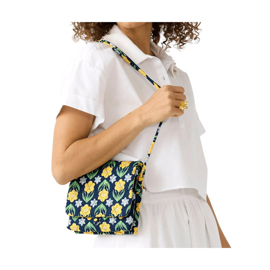 Navy floral crossbody bag with yellow and green flowers and a flap closure, worn over a white shirt