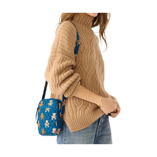 Beige cable-knit turtleneck sweater with a blue quilted crossbody bag