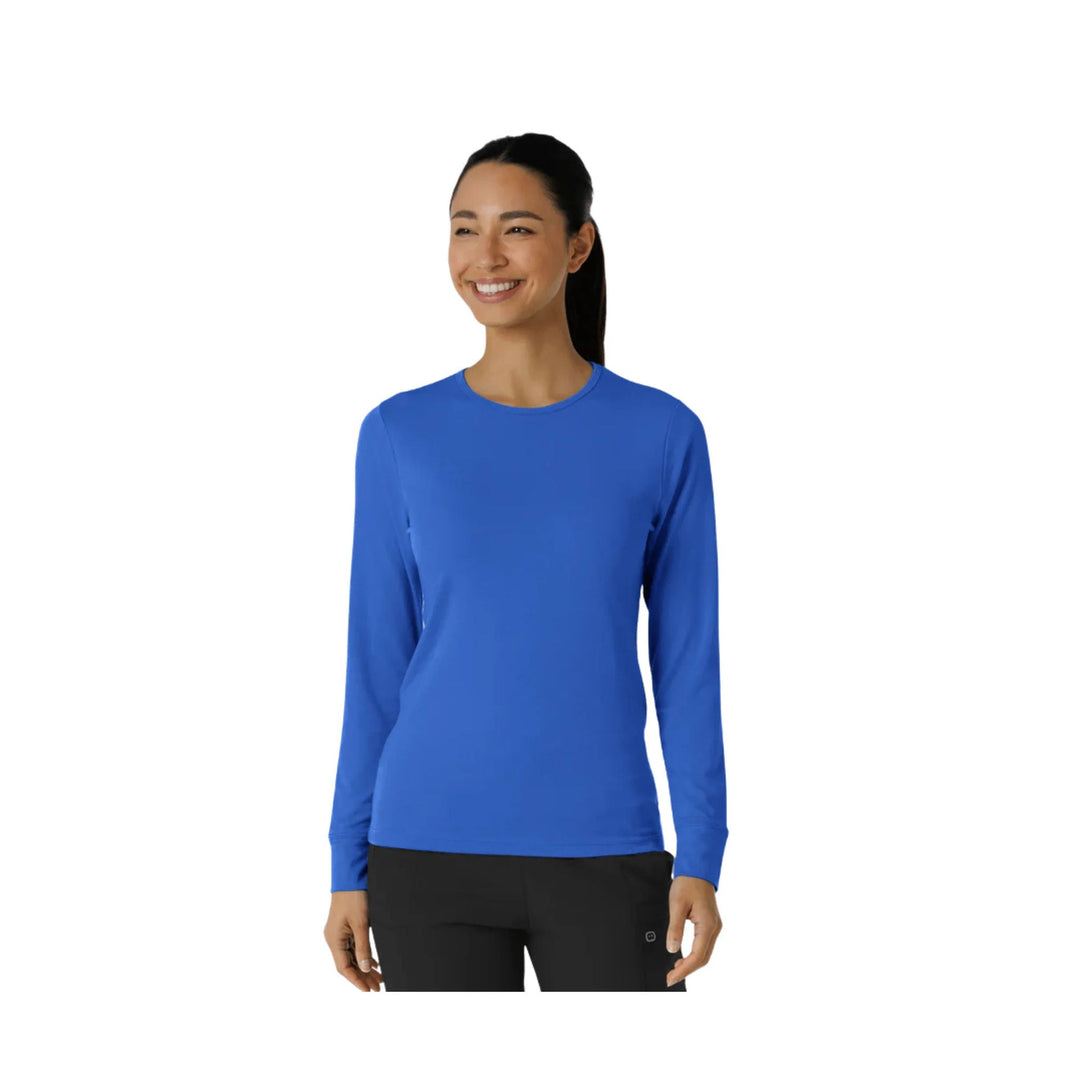Woman wearing a blue long-sleeve crewneck shirt with black pants