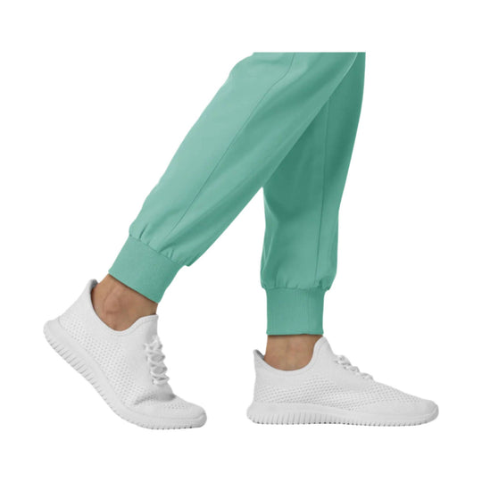 Mint green jogger scrub pants with ribbed ankle cuffs, shown with white sneakers