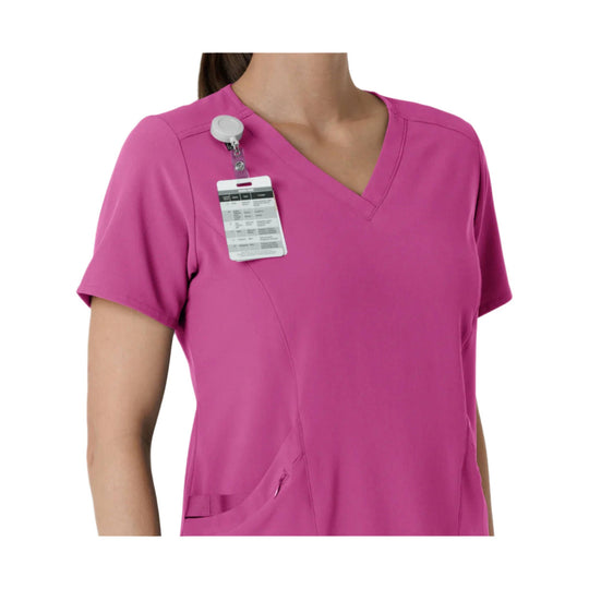Short-sleeve pink scrub top with a clipped tag on the chest