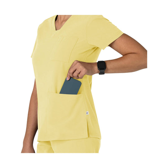 Yellow short-sleeve scrub top with chest and front pockets, shown on a model holding a phone