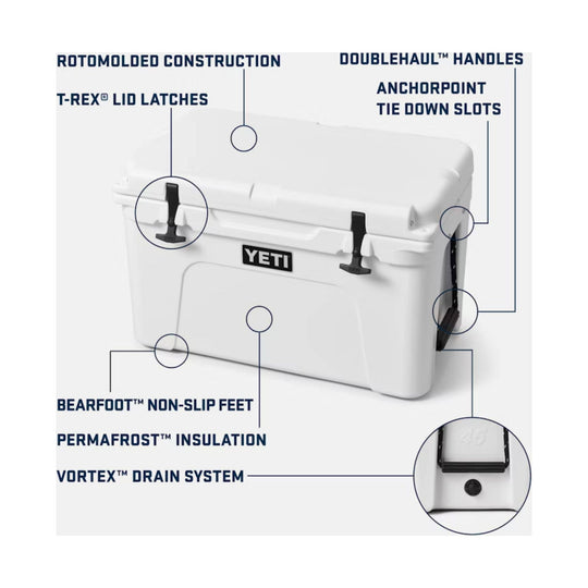 White hard-sided cooler with black latches and handles, labeled with feature callouts for rotomolded construction, anchorpoint tie down slots, and drain system.