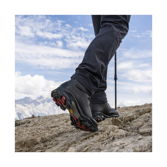 Black leather hiking boots on rocky terrain, shown from the side and sole