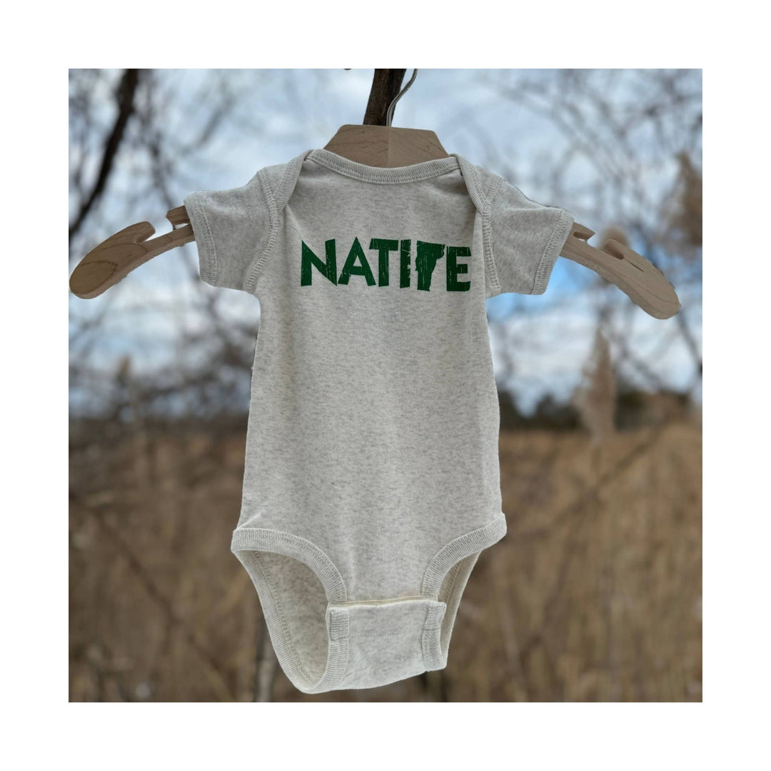 Light gray infant onesie with green NATIVE text on a wooden hanger