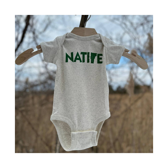 Light gray infant onesie with green NATIVE text on a wooden hanger