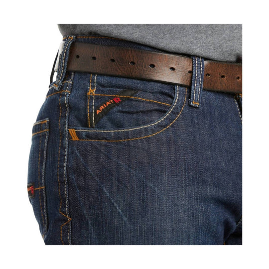 Close-up of dark blue denim jeans with contrast stitching, a brown leather belt, and an Ariat logo on the front pocket