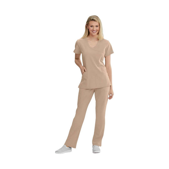 Woman wearing a beige V-neck scrub top and matching scrub pants with gray slip-on shoes