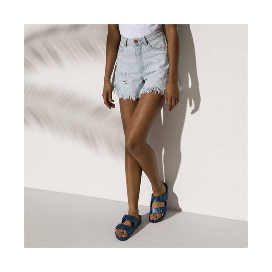 Blue double-strap sandals on a model wearing light denim shorts