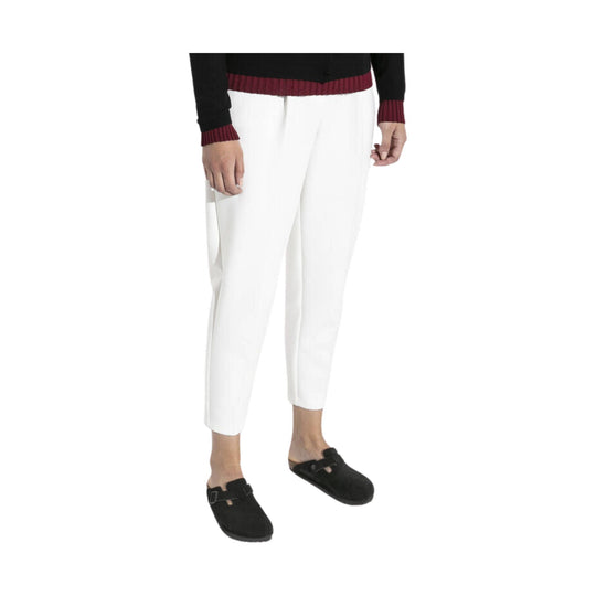 Black suede slip-on clogs with buckle strap, shown with white pants
