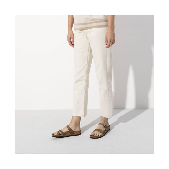 Cream straight-leg pants with brown leather sandals on a model