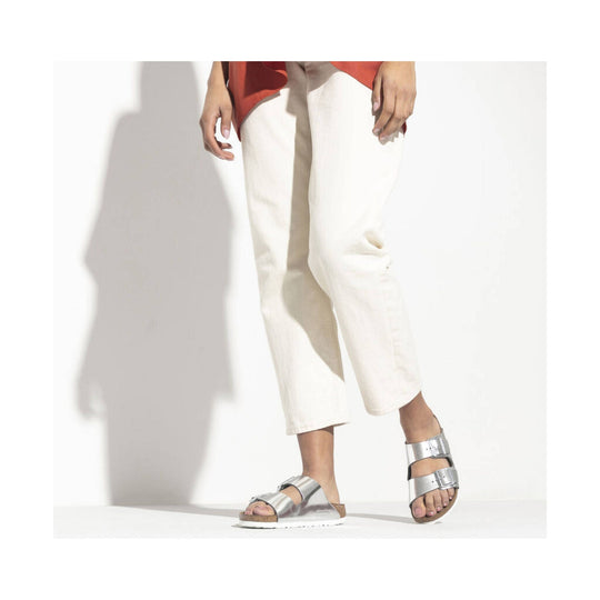 Silver double-strap slide sandal on a model with white cropped pants