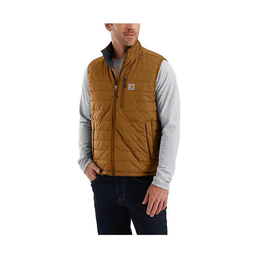 Brown quilted insulated vest with front zipper and chest logo patch over a light gray long-sleeve shirt