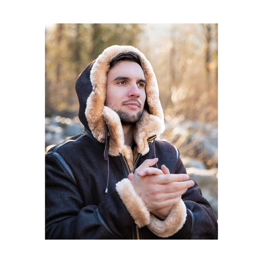Dark brown shearling-lined bomber jacket with hood and fur-trimmed cuffs, shown on a man outdoors