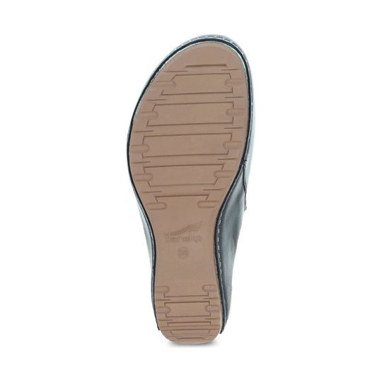 Black clog shown from the sole with a tan tread and visible Dansko branding