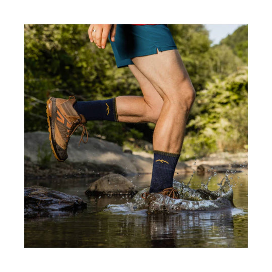 Brown hiking boot splashing through a creek on a runner’s foot