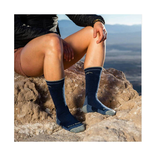 Navy midweight hiking socks with light gray toes and heels, worn on a person sitting on rocks