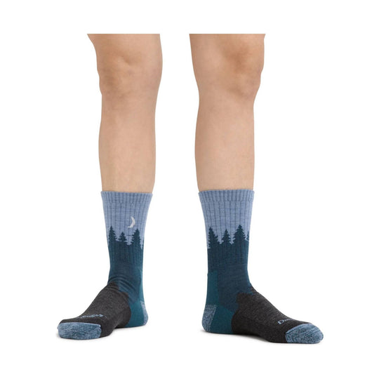 Pair of blue and dark gray crew hiking socks with forest and moon pattern, shown on legs