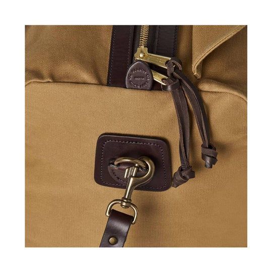 Tan canvas duffel bag with brown leather trim, brass hardware, and a front D-ring strap
