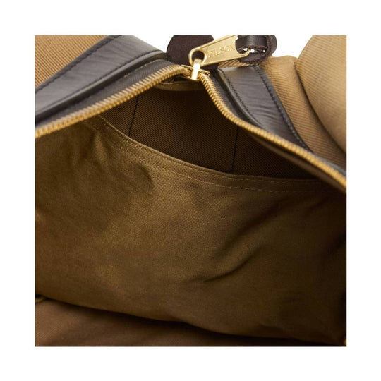 Tan canvas duffel bag interior with dark leather trim and a gold zipper pull