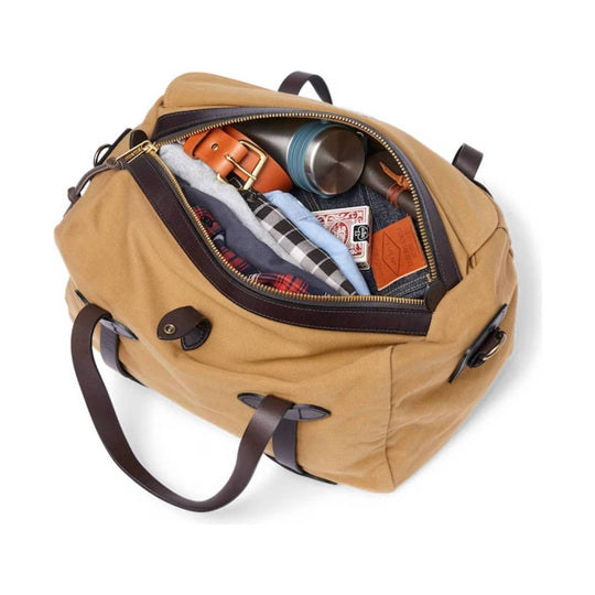 Tan canvas duffel bag with leather straps, open top zipper, and packed with folded clothes and a metal bottle