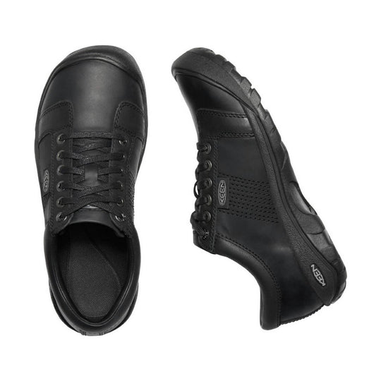 Black low-top leather sneaker with lace-up front, rounded toe, and textured sole