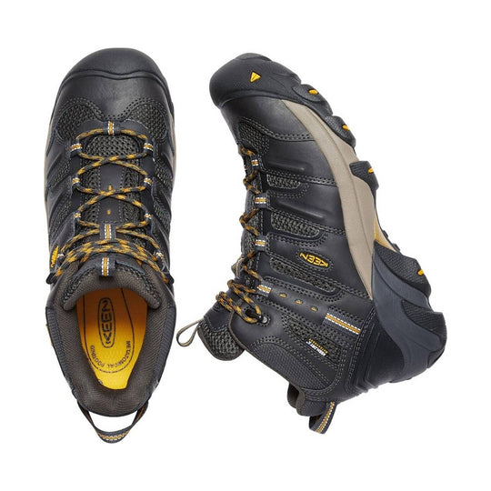 Black mid-height work boot with yellow accents, mesh panels, and thick lug sole shown from top and side