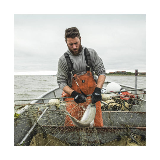 Black gloves worn by a fisherman holding a fish on a boat