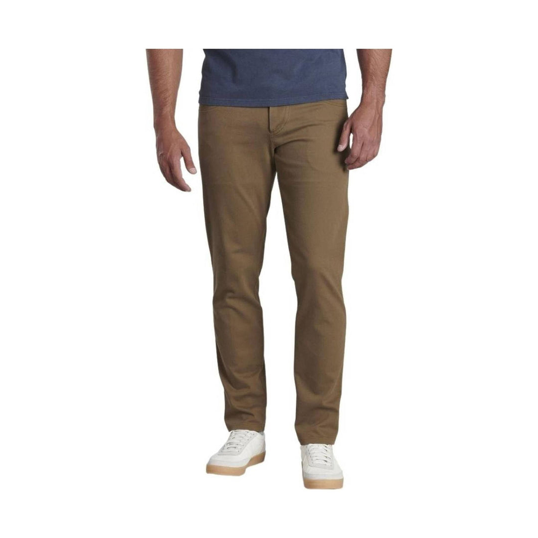 Brown tapered pants shown on a model with a blue shirt and white sneakers