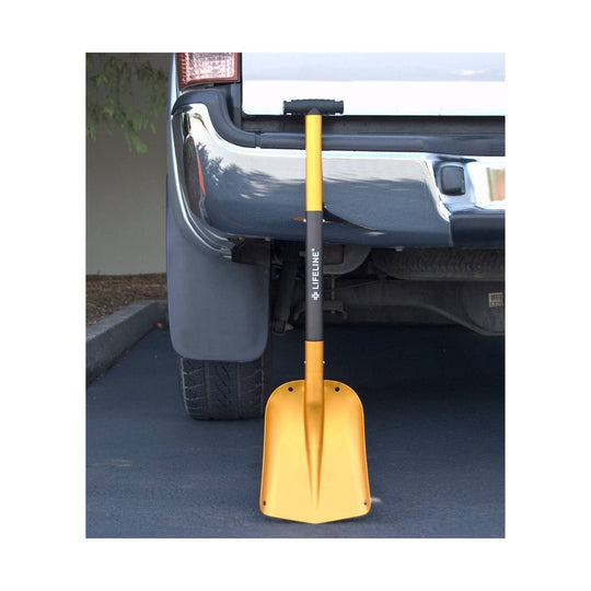 Yellow snow shovel with black handle leaning against the back of a pickup truck