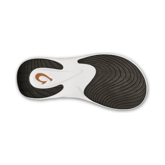 Black and white sandal outsole with curved tread grooves and a small orange logo mark