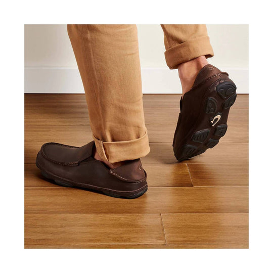 Brown leather slip-on loafers with rubber outsoles, shown on a person wearing tan pants