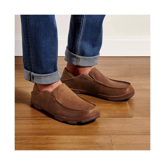 Brown slip-on leather loafers with moc-toe stitching, worn with cuffed blue jeans