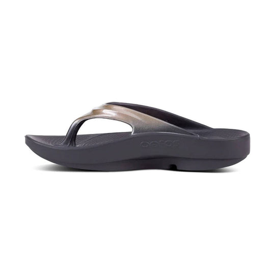 Dark gray flip-flop sandal with a metallic tan strap and thick cushioned sole, side view