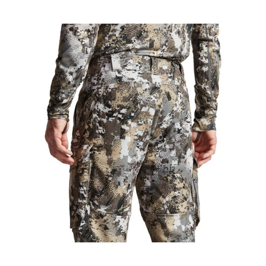 Camouflage hunting pants shown from the back on a model, with cargo pockets and a belted waist