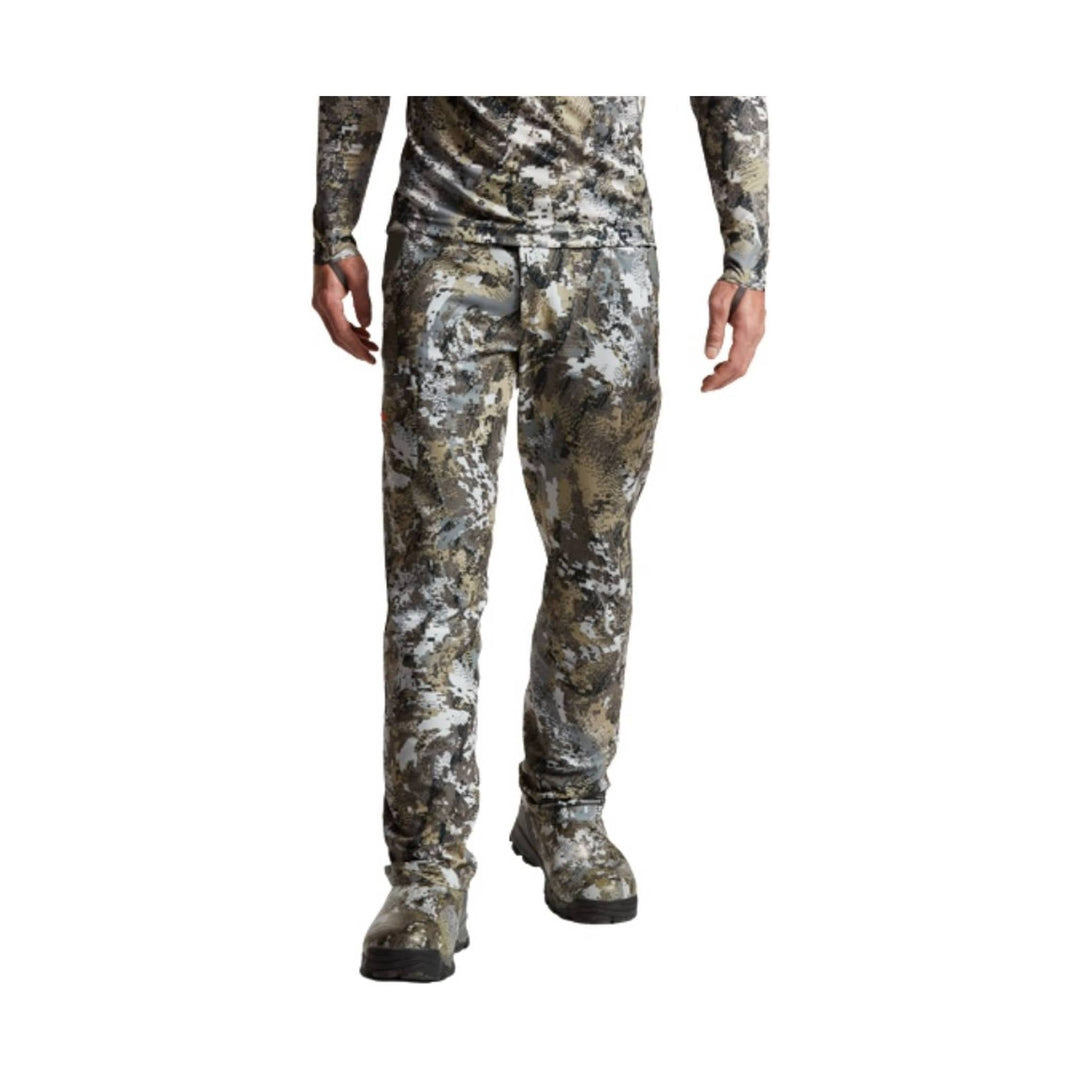 Camouflage long-sleeve top and pants worn with boots, shown from the waist down
