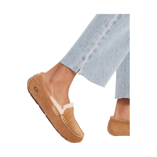 Tan suede slip-on moccasin with white shearling trim and UGG logo on the heel