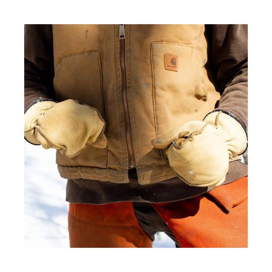 Tan leather mittens with fleece cuffs on a person wearing a brown work jacket
